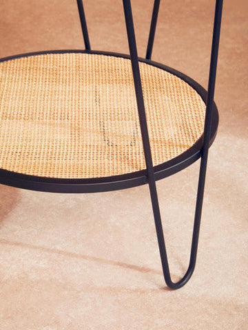 Depok rattan side table with black metal hairpin legs and woven cane top featuring a lower shelf for storage