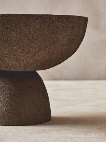 A matte brown ceramic pedestal bowl with textured grey earthy surface and sleek modern design perfect for serving