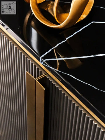 Dervio grey four door sideboard with black marble top featuring gold-toned metallic trim and golden sculptural decor