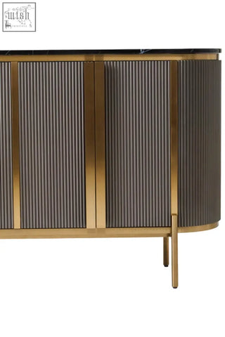 Modern grey four door sideboard with vertical ribbed doors framed in polished gold and black marble top