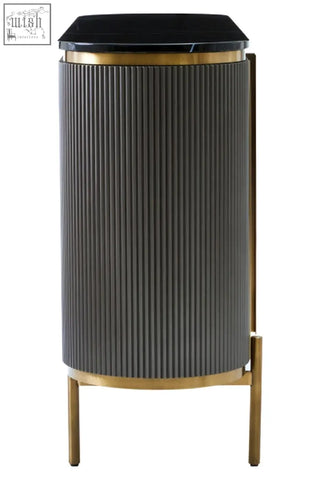 Black marble top side table with vertical ribbed grey metal body and gold tone accents next to dervio grey four door sideboard