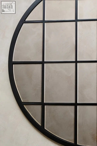 Black-framed descartes round metal wall mirror with circular shape and grid of square mirrored panels