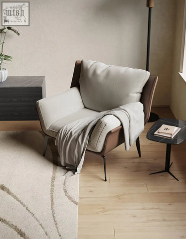Modern dias armchair with corduroy upholstery featuring a brown leather frame and plush cushioning with gray throw blanket