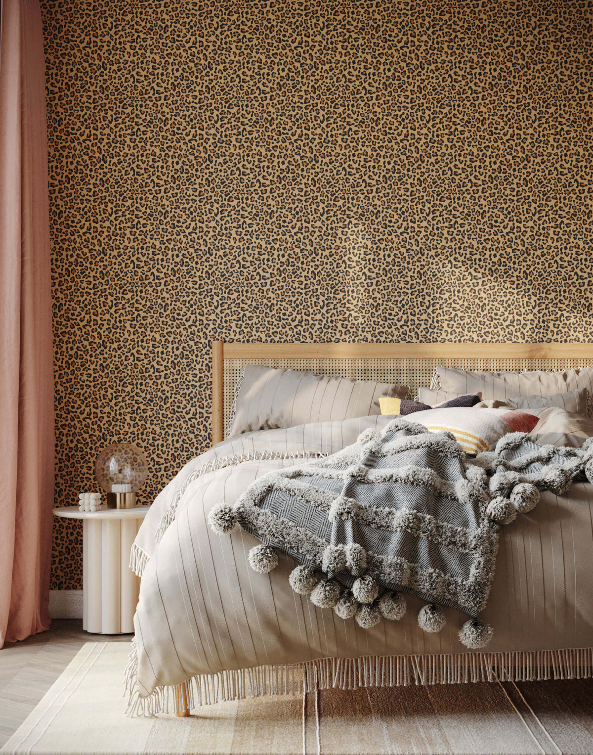 A cozy gray knit diego blanket with fluffy pom-poms and fringe draped on a bed perfect for leopard print wallpaper rooms