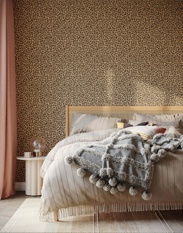 A cozy gray knit diego blanket with fluffy pom-poms and fringe draped on a bed perfect for leopard print wallpaper rooms