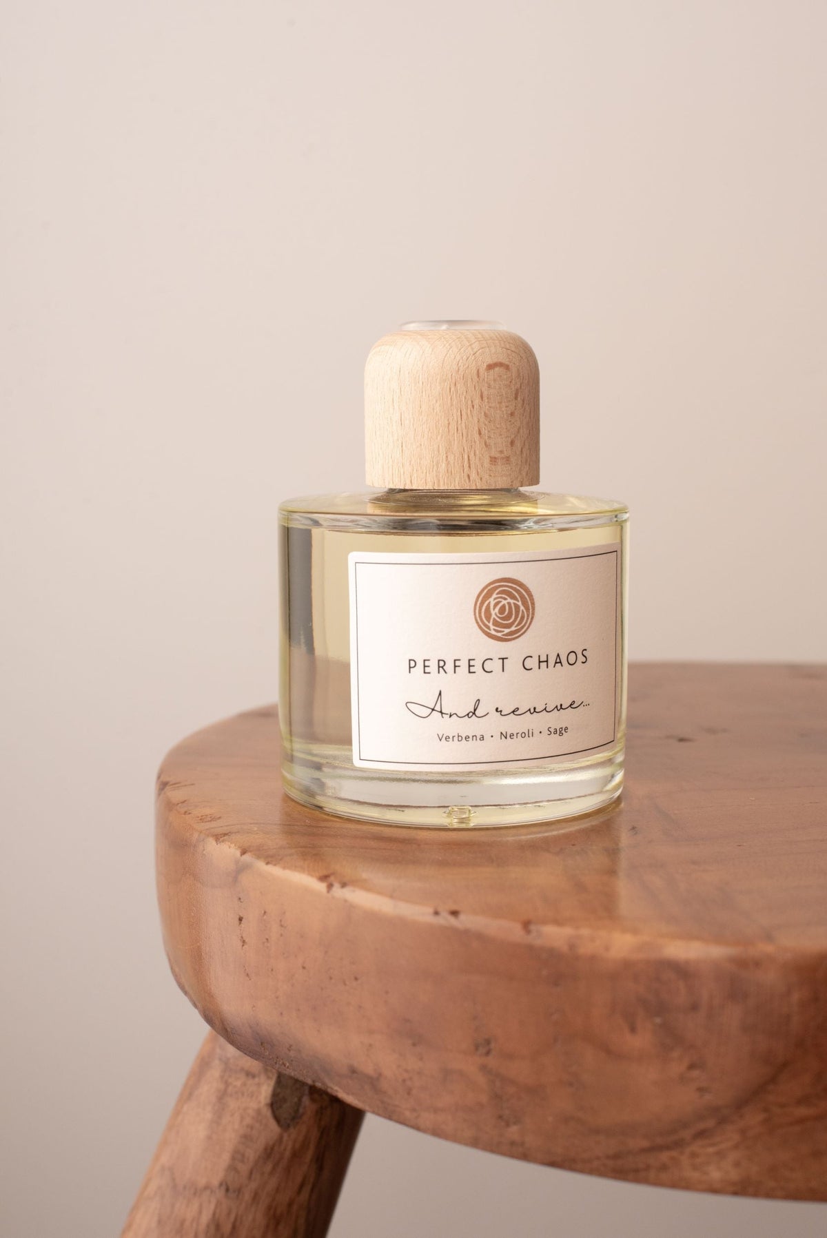 A clear glass diffuser refill bottle with a light wood cap and pale yellow liquid inside