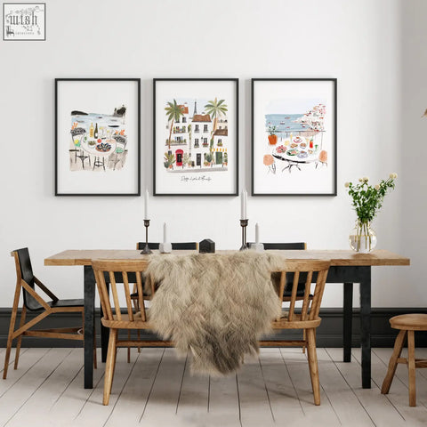 Three framed watercolor amalfi coast prints in soft colors hanging on a dining room wall above a wooden table