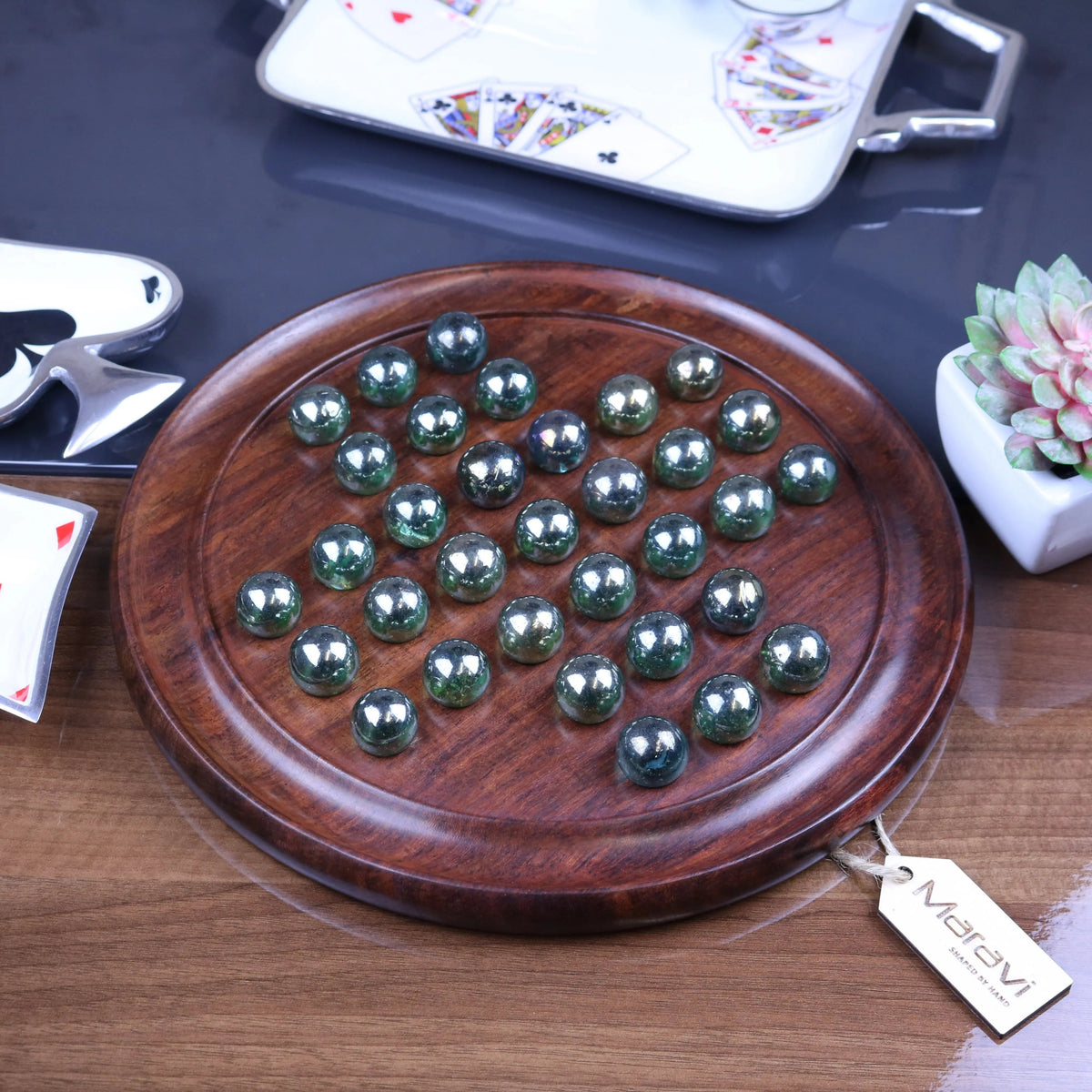 A dinod large wooden solitaire game set with a polished dark wood board and glossy green and silver metallic marbles arranged in rows
