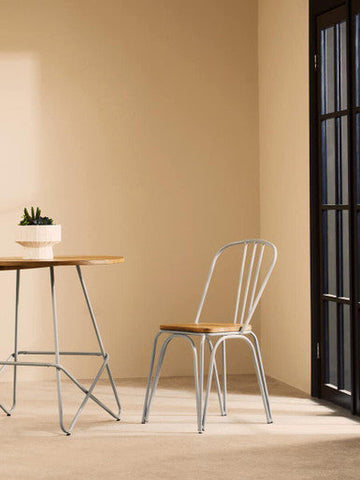 Minimalist metal chair with slender vertical spindles and elm wood seat complements district grey metal dining table