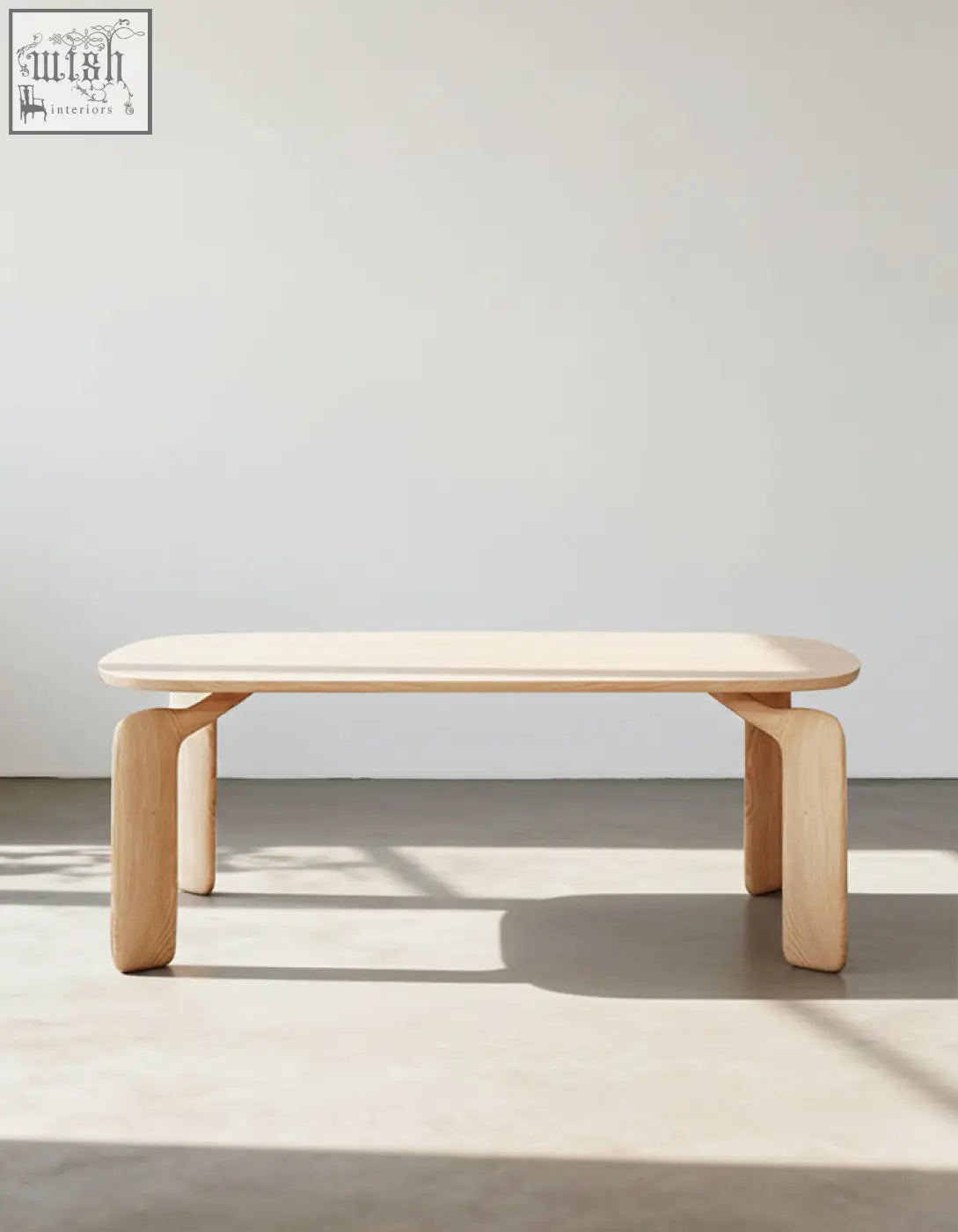 Minimalist light wood domingo dining table with smooth rounded top and sleek curved legs in sintered stone finish