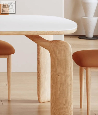 A sleek modern domingo dining table with a smooth white sintered stone top and sculpted light oak legs