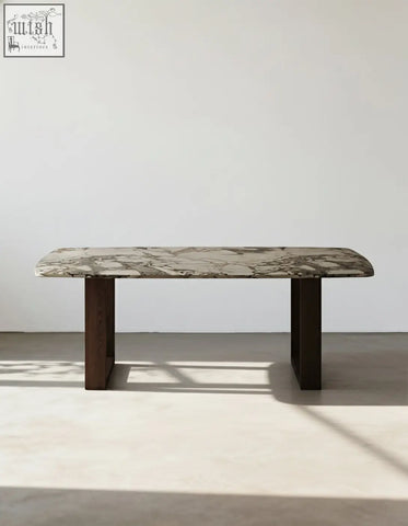 A sleek donovan dining table with a polished gray and white marble top and dark wood legs for modern dining spaces