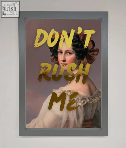 A framed dont rush me foil print featuring a woman in a white off the shoulder gown with a brown bow on her hair