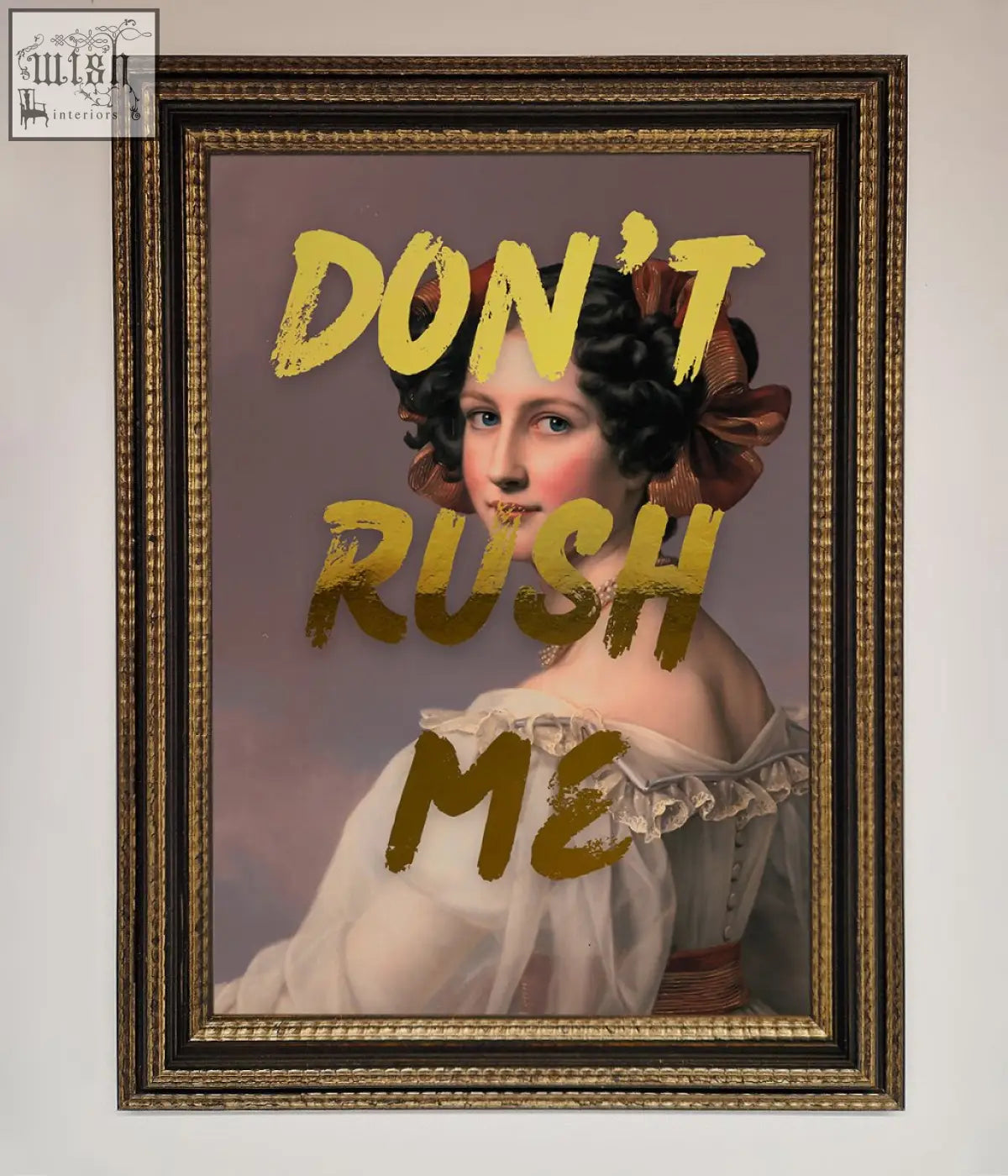 A framed dont rush foil print featuring a woman in a white gown with dark curls and a brown bow about shipping time