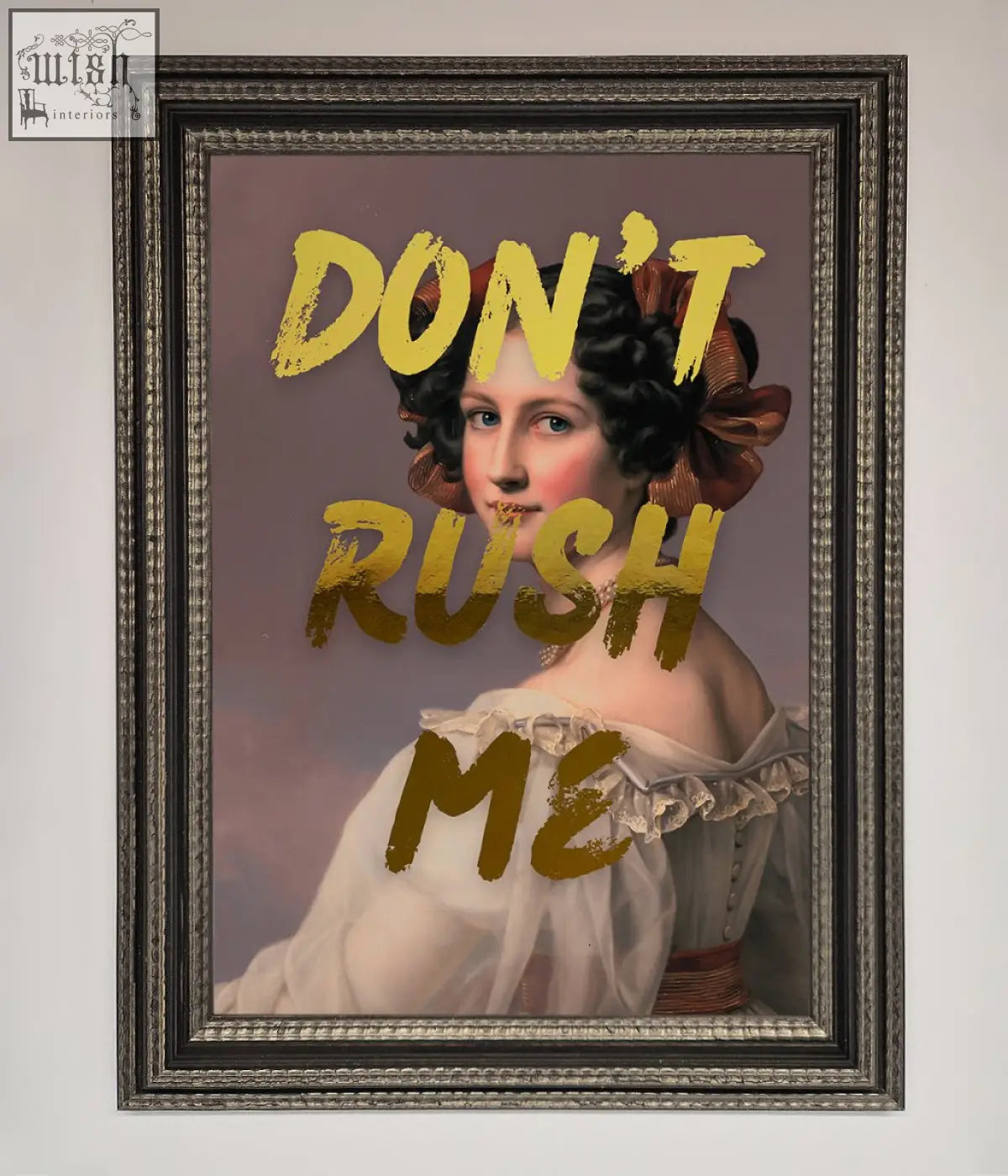 A framed dont rush me foil print featuring a woman in a white off-the-shoulder gown with a brown bow on her hair