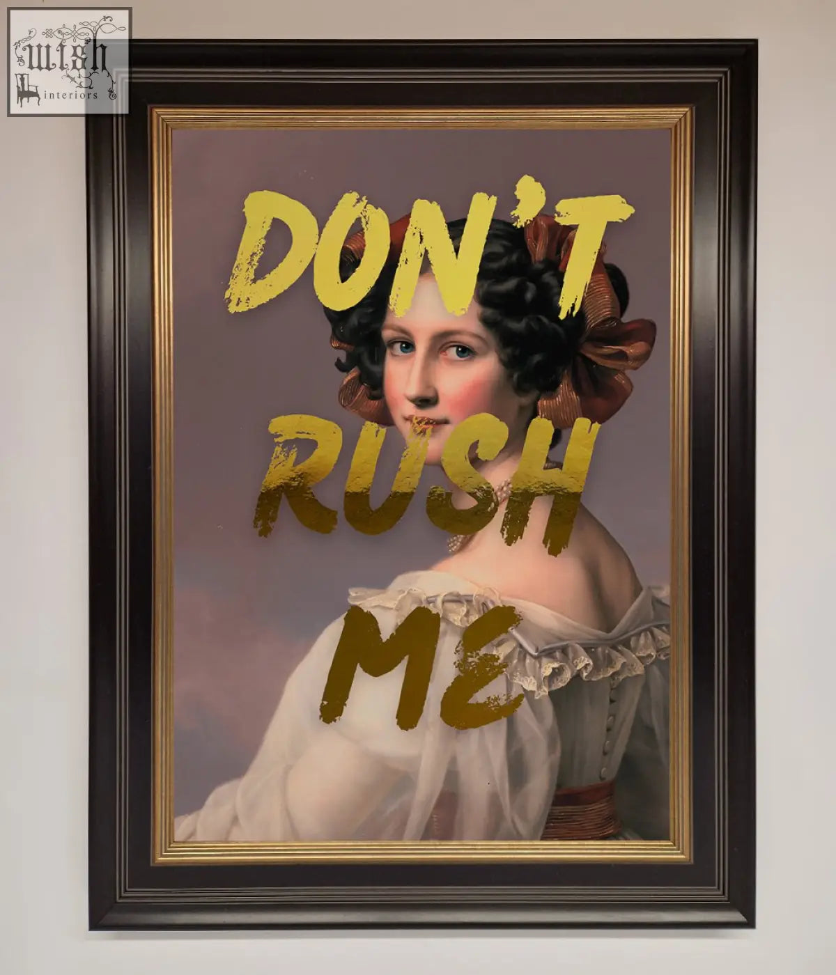 A framed dont rush me foil print portrait of a woman in a white off-the-shoulder gown with a large brown bow