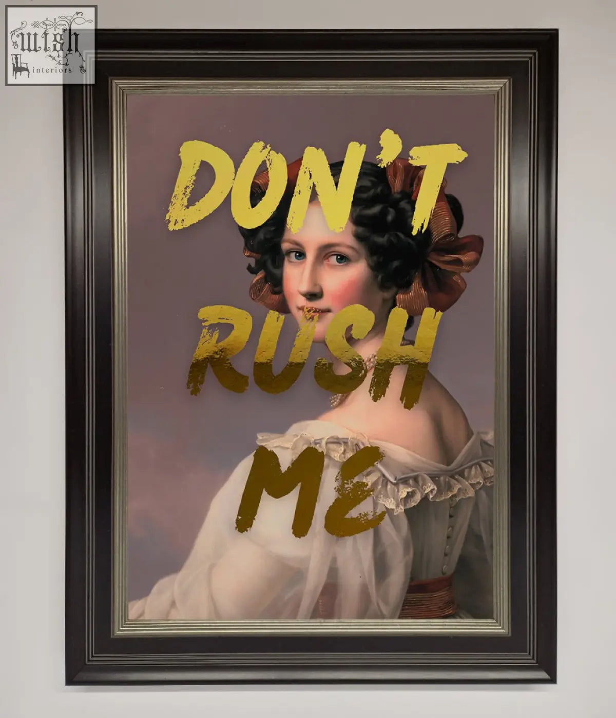 A framed dont rush foil print featuring a woman in a white gown with dark curly hair and bold gold lettering about shipping time