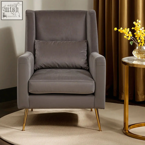 A sleek doucet grey velvet chair with gold finish legs and a matching cushion for stylish seating