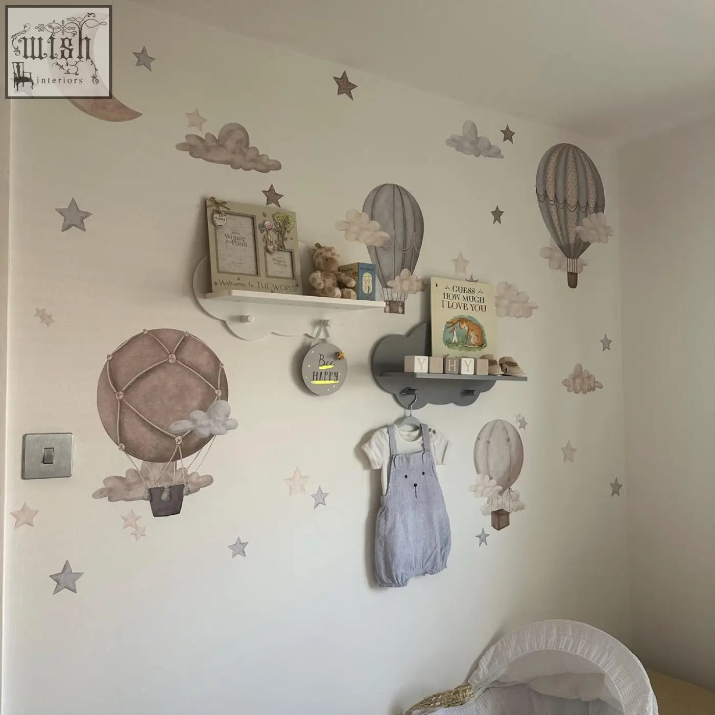 Light blue denim overalls with white sleeves and black buttons hanging next to dreamy hot air balloons wall decals