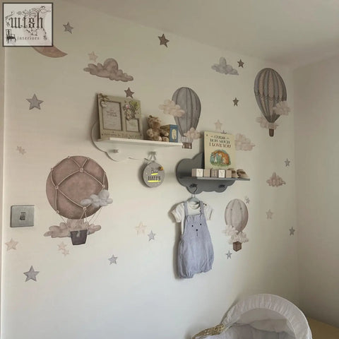 Light blue denim overalls with white sleeves and black buttons hanging next to dreamy hot air balloons wall decals