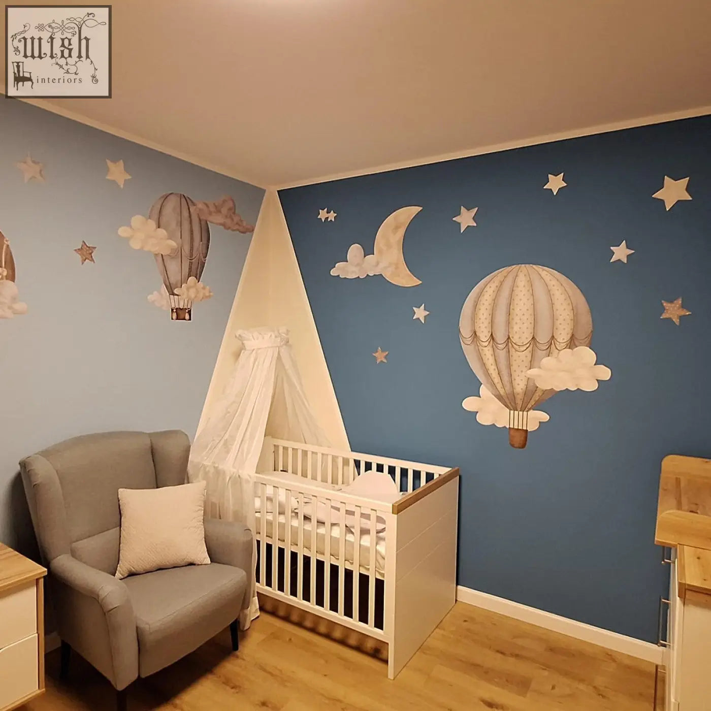 White wooden crib with canopy and soft bedding in nursery decorated with dreamy hot air balloons wall decals