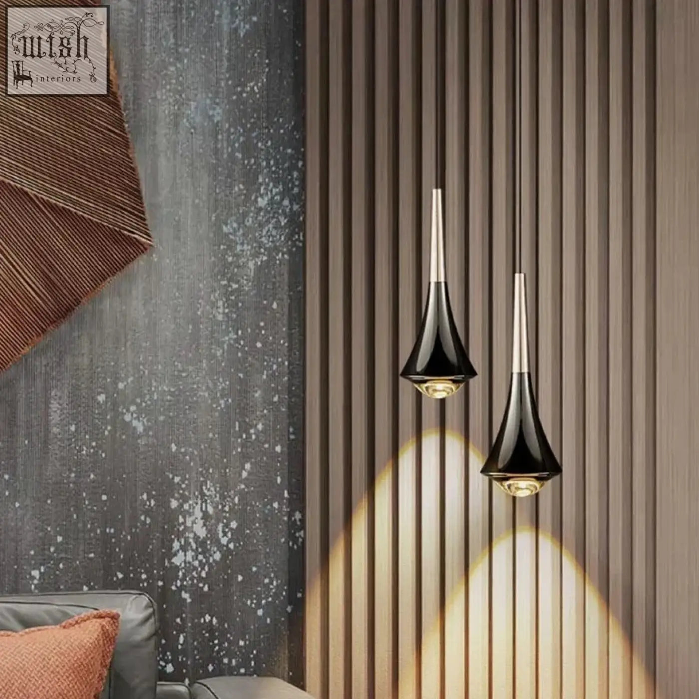 Two sleek black dropping pendant lights with metallic stems hang casting warm golden led integrated light downward