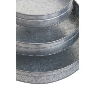Stacked three round galvanised steel trays with wooden handles and a rustic textured finish in silver gray