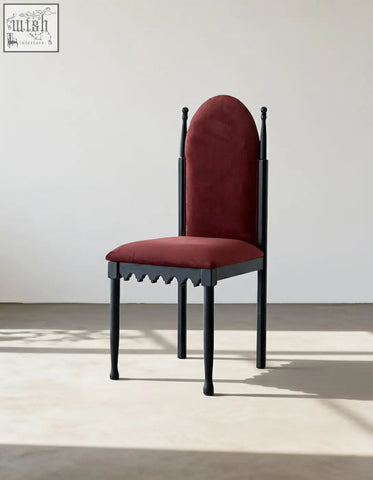 A striking black wooden ealing high-back dining chair with a plush deep red velvet seat and backrest