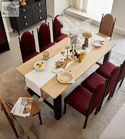Light wood dining table with black legs and a white runner paired with an ealing high-back dining chair