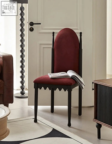 A plush burgundy velvet ealing high-back dining chair with scalloped black wooden legs perfect for your dining room