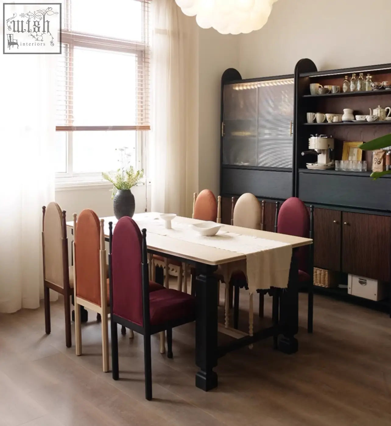 A rectangular dining table with a light wooden top and dark legs paired with ealing high-back dining chairs