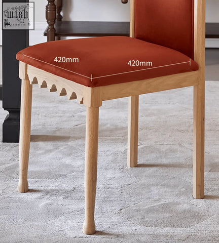 A rustic ealing high-back dining chair with terracotta velvet seat and scalloped carved wooden detailing