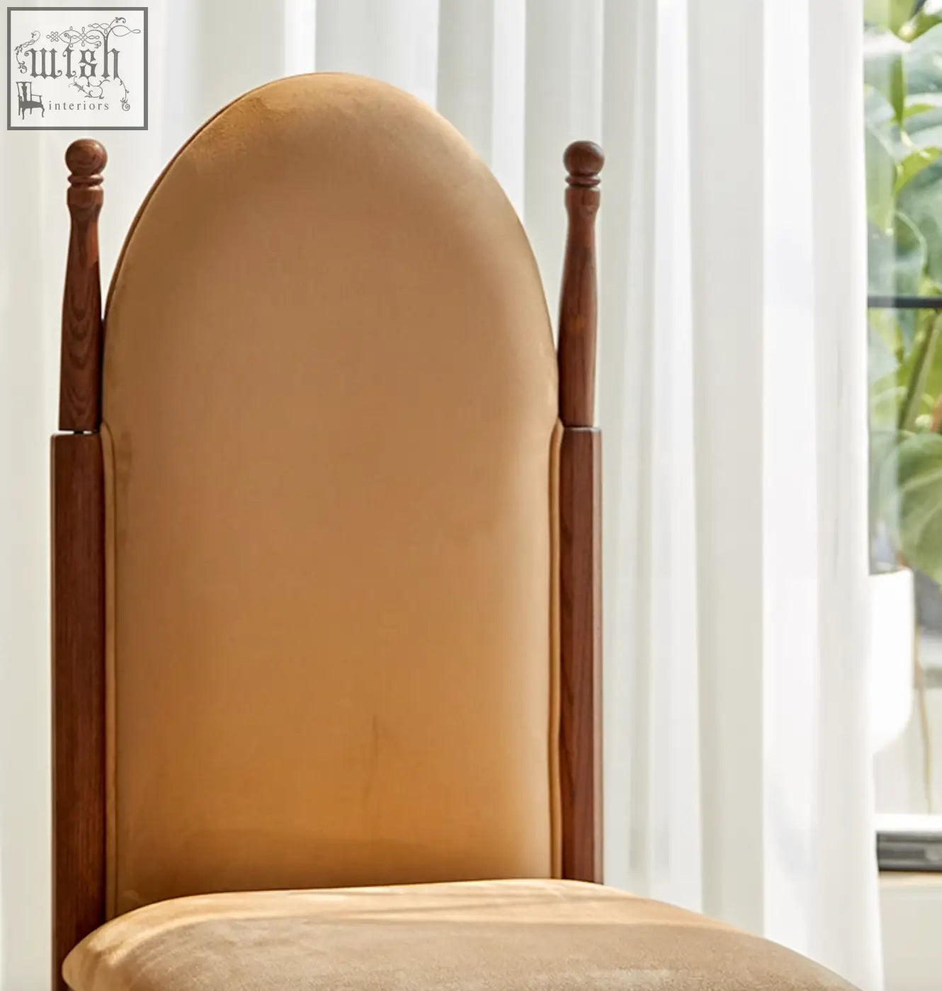 A tall elegant ealing high-back dining chair with warm brown wood and soft tan velvet upholstery