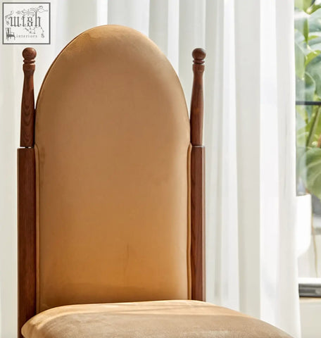A tall elegant ealing high-back dining chair with warm brown wood and soft tan velvet upholstery