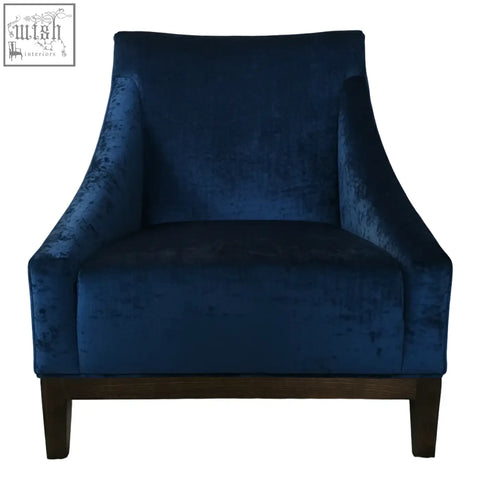 Deep blue velvet ease arm chair with sleek modern design and dark wood legs for stylish comfort
