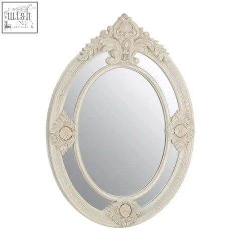 Eclipse antique white oval mirror with a distressed antique white ornate frame and detailed white ornate wall design