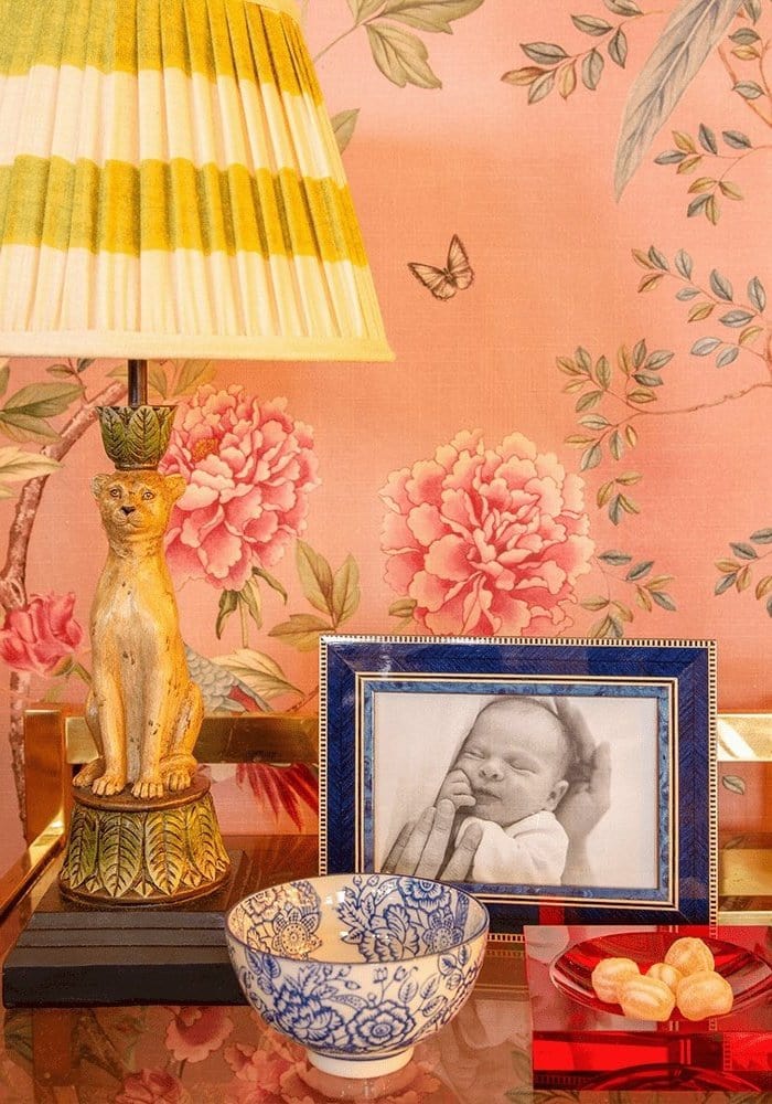 A decorative table lamp with a yellow cream striped shade on a golden cat base next to an eco marquetry photo frame