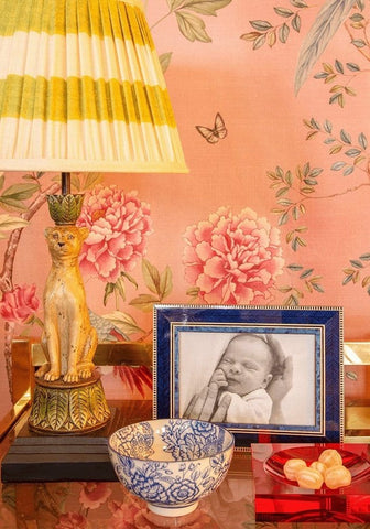 A decorative table lamp with a yellow cream striped shade on a golden cat base next to an eco marquetry photo frame
