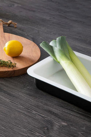 Ecocook black rectangular roasting dish with a white and black rectangular tray holding two green leeks