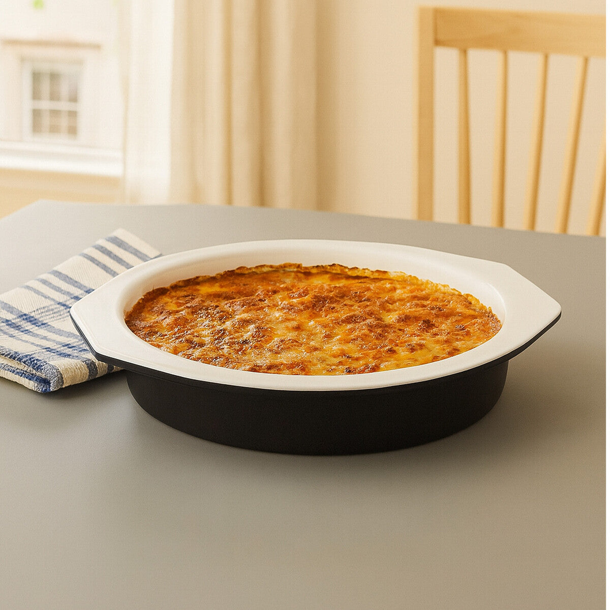 Ecocook black round 27cm ceramic baking dish with handles holding golden brown baked casserole inside