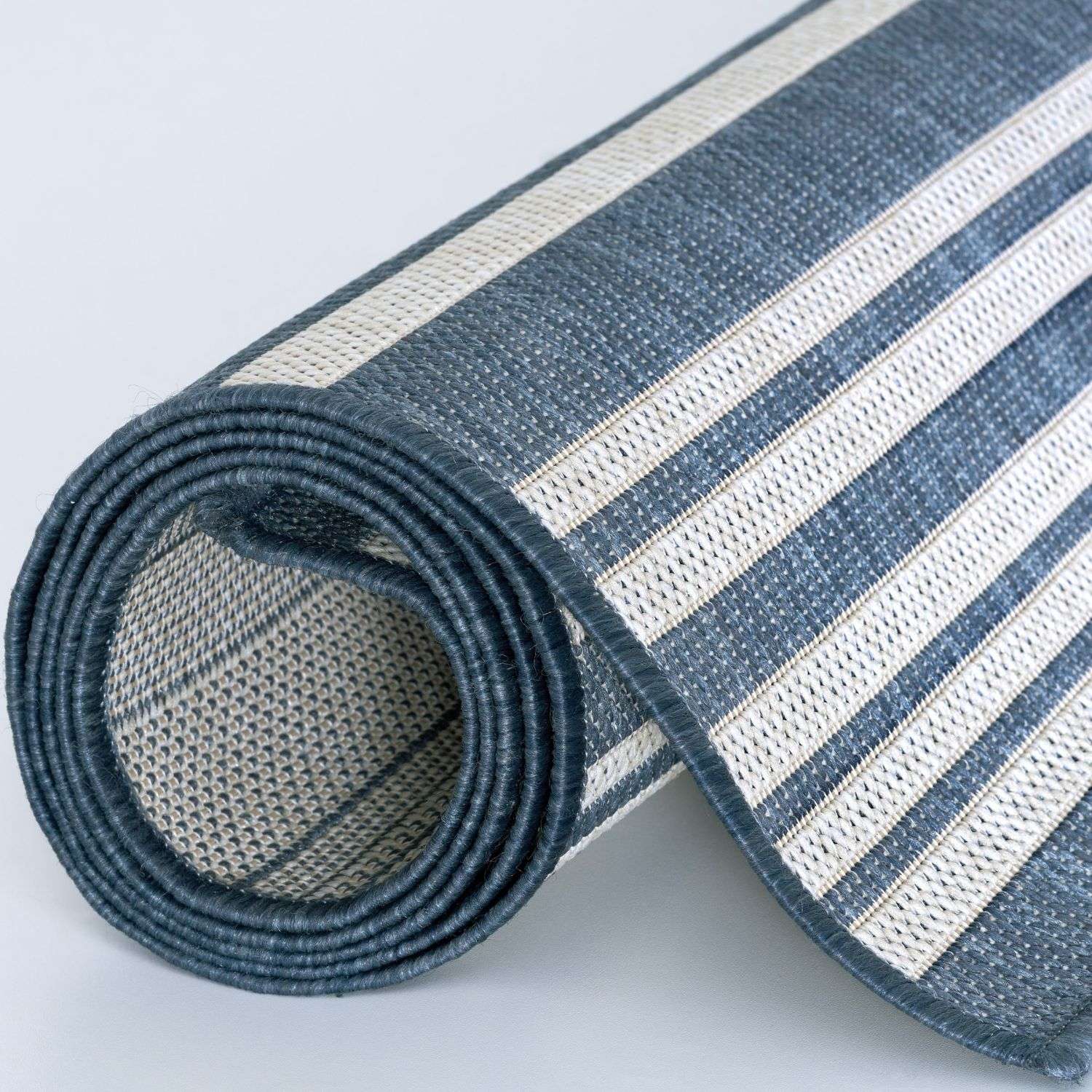 Rolled-up ecology outdoor rug blue with bold navy and off-white stripes woven texture and finished edges