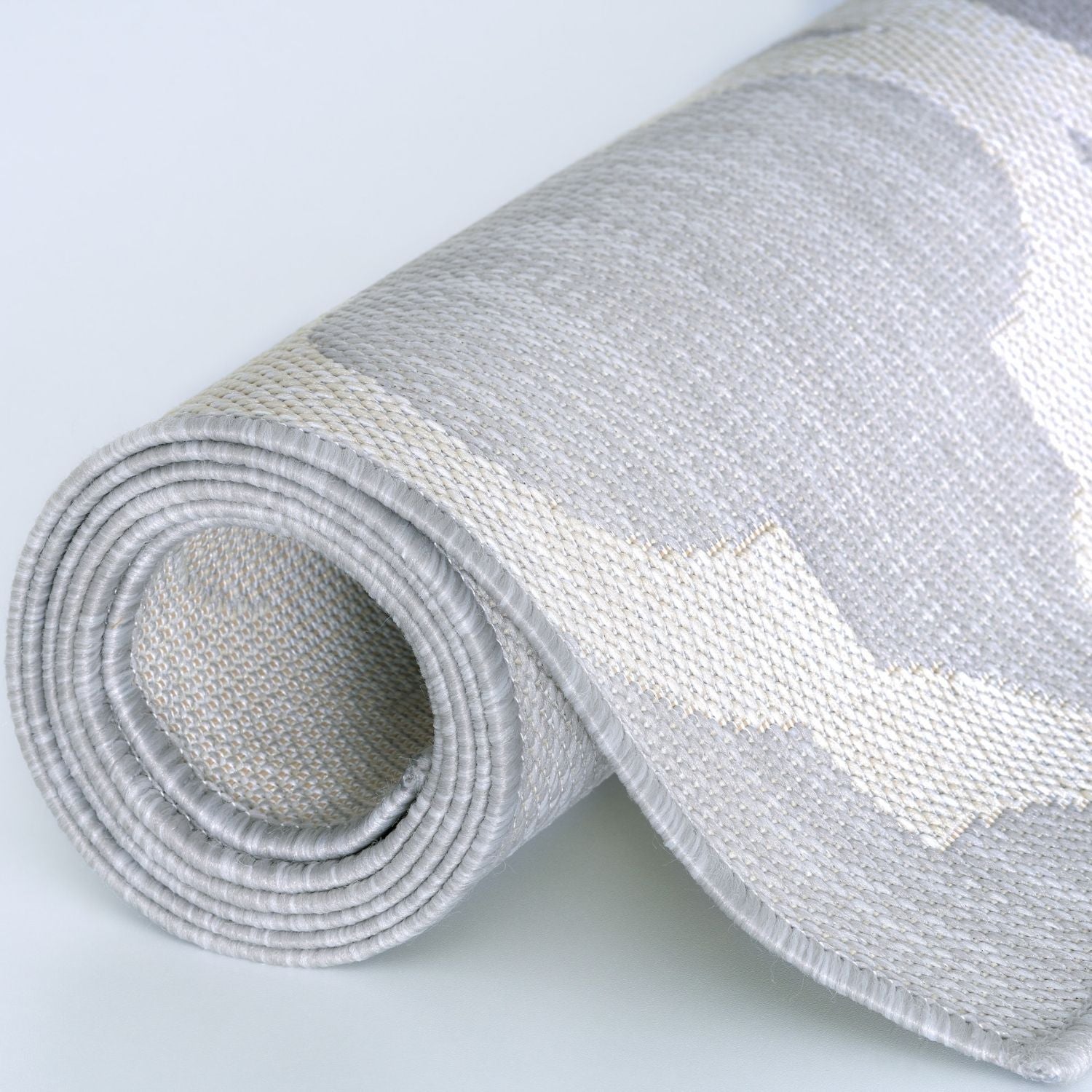 Rolled-up gray and white geometric-patterned ecology outdoor rug with woven texture perfect for outdoor use