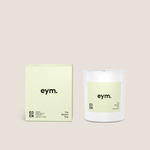 A minimalist white glass standard candle named the blissful one by eym with a pale green label and matching box