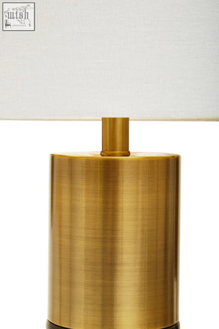 A sleek edgar black marble and gold table lamp with a cylindrical brass base and a white fabric shade