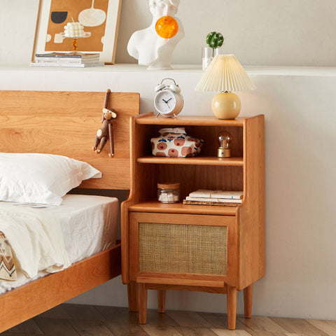 Light brown solid wood edith bedside table with woven cane panel door and two open shelves for storage