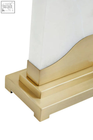 Gold-toned brass base with a stepped design holds a white glass shade in the edith table lamp with white marble base