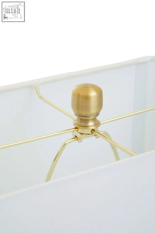 Gold-toned metal base with rounded knob and slender arms of the edith table lamp in white marble and gold