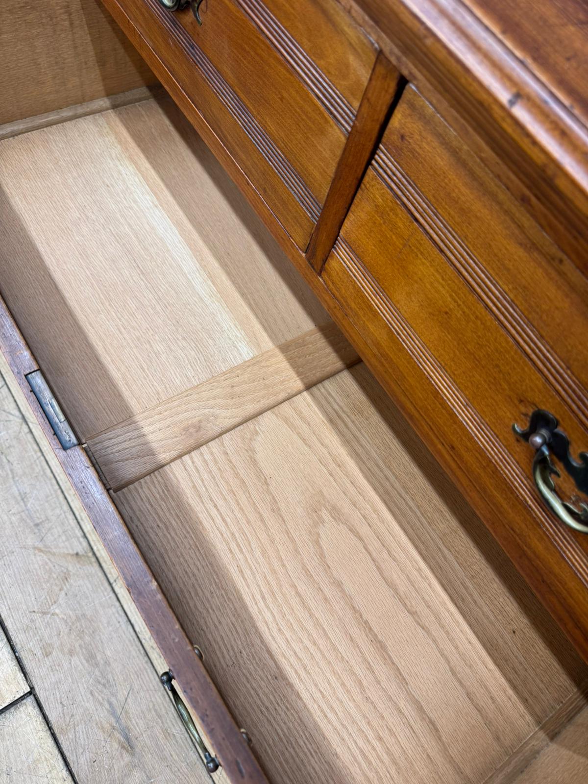 A polished edwardian walnut chest of drawers with carved fronts and brass handles for antique bedroom storage