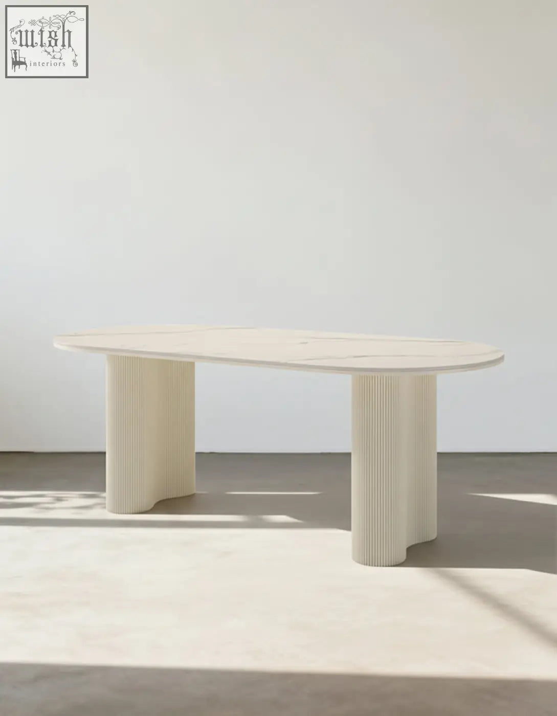 Cream-colored oval white dining table with fluted sculptural legs and smooth marble top for white dining spaces