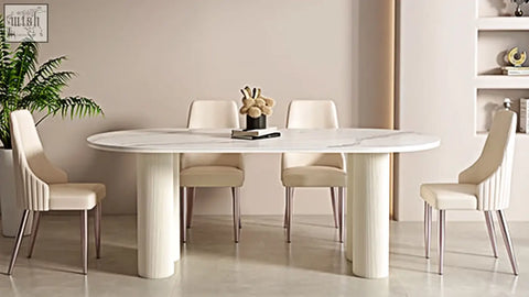 Eira white dining table with white marble top and cylindrical legs paired with cream upholstered chairs for dining room